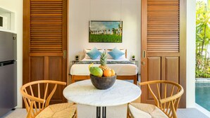 Una habitación con una cama, un frutero sobre una mesa y un cuadro en la pared.
