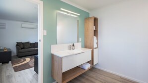 Un baño moderno con un tocador blanco, estantes de madera y un espejo.