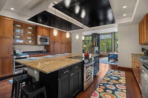 Une cuisine moderne dotée de plans de travail en granit, d’appareils électroménagers en acier inoxydable et de meubles en bois.