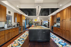 A modern kitchen with wooden cabinets, stainless steel appliances, and a colorful patterned floor.