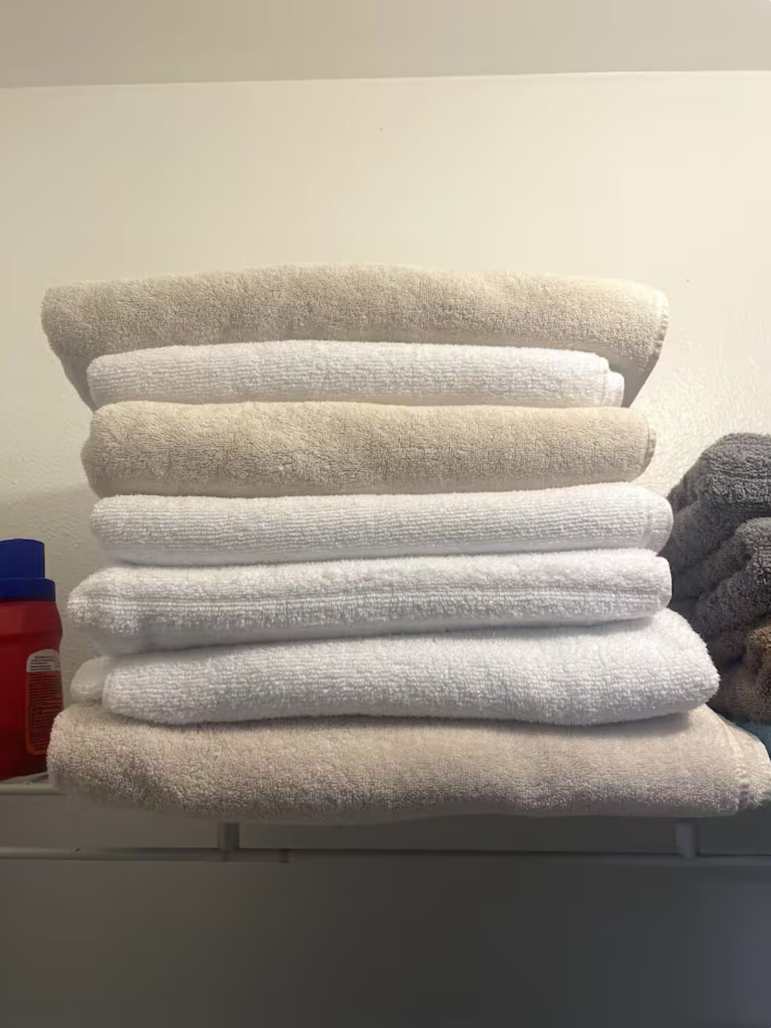 A stack of folded towels in various shades of white and beige.