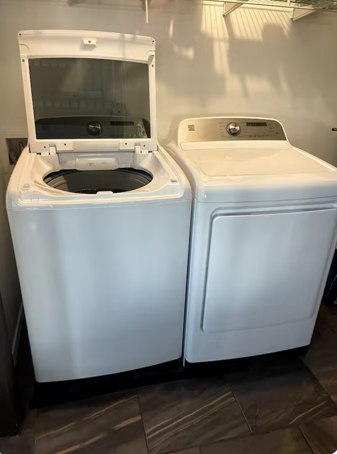 A front-loading washing machine and dryer side by side in a laundry room with a tiled floor.