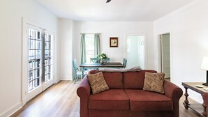 A living room with a red sofa, a dining table with chairs, and a ceiling fan. - Charm of Crestview! 5-bedroom house in serene Knoxville! (Knoxville)