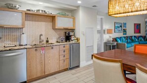 A modern kitchen with wooden cabinets, a built-in oven, and a dining area with a wooden table and orange chairs. - 1 bedroom Presidental - Margaritaville Resort, St Thomas (Saint Thomas)