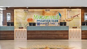 A reception desk with a map backdrop, a sign reading 'Margaritaville Cation Club,' and a tropical-themed mural. - 1 bedroom Presidental - Margaritaville Resort, St Thomas (Saint Thomas)