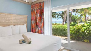 A hotel room with a bed, a nightstand, a lamp, and a view of the outdoors. - 1 bedroom Presidental - Margaritaville Resort, St Thomas (Saint Thomas)