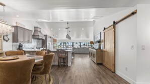 Een ruime keuken met een centraal eiland, houten kastjes en een schuifdeur in boerderijstijl.