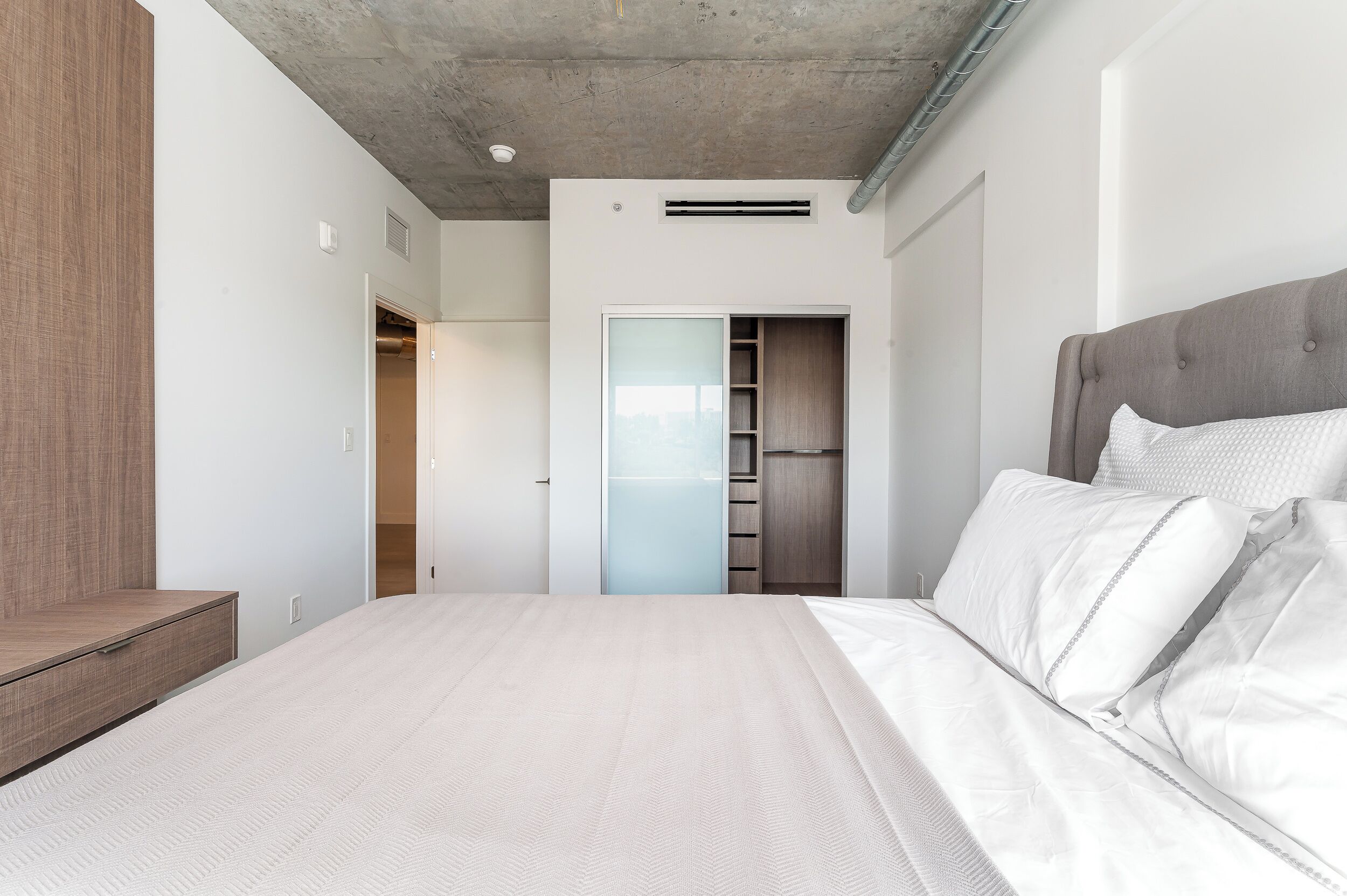 Un dormitorio moderno con una cama grande, armario empotrado y un closet visible.