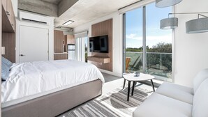 A modern bedroom with a large bed, a TV, and a balcony with a view. - Milan Aventura Hotel (Ojus)