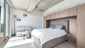 Un dormitorio moderno con una cama grande, un espacio para sentarse y vistas al exterior.