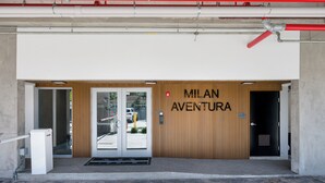A building entrance with a wooden facade and a sign that reads "Milan Aventura." - Milan Aventura Hotel (Ojus)