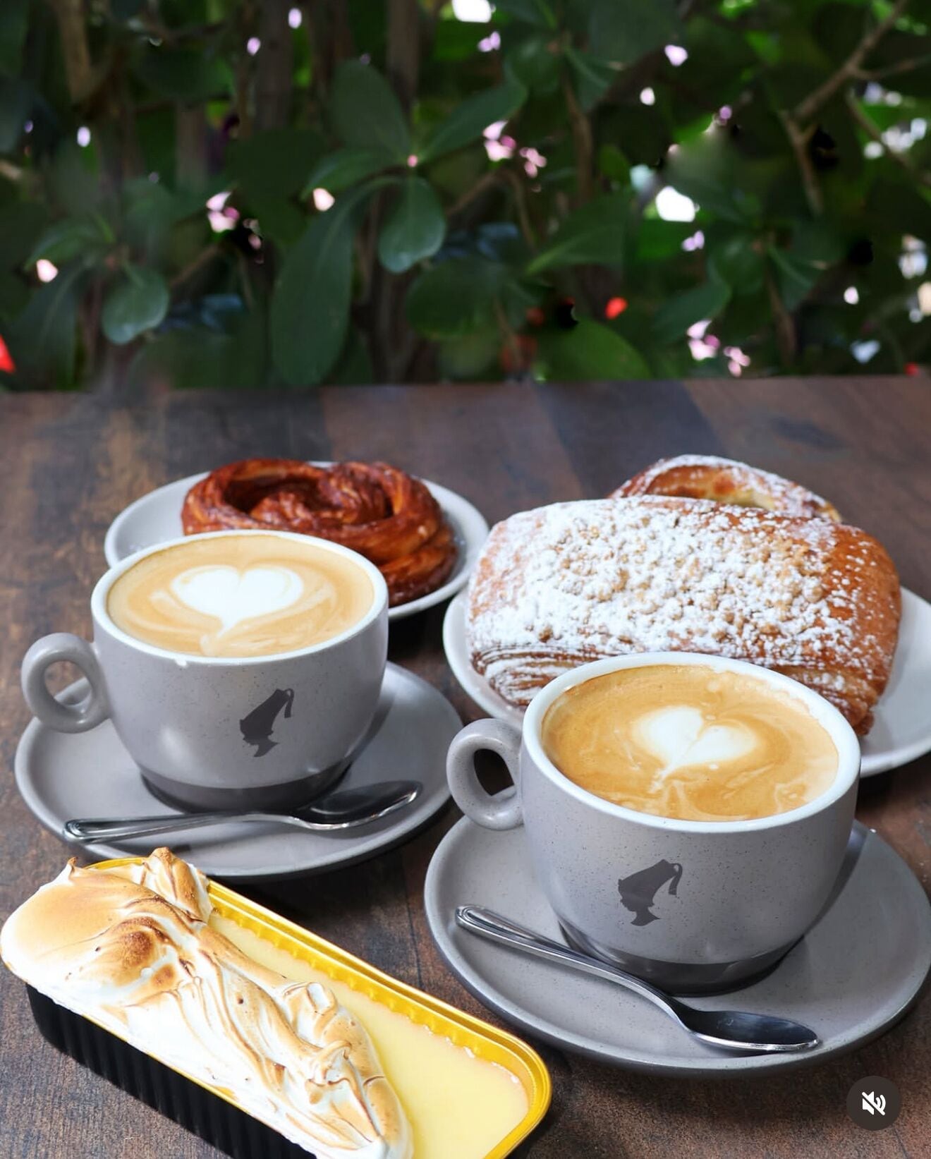A table with two cups of coffee, a pastry, and a dessert.