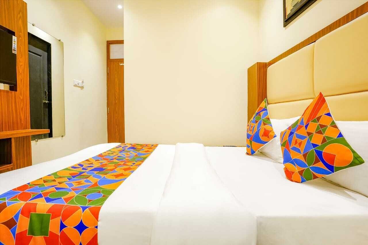 A hotel room with a bed, a wooden door, and a window.