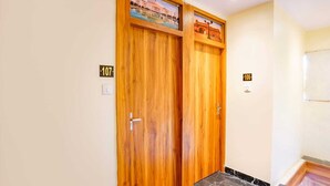 A hallway with two wooden doors, each marked with a number. - Hotel Emirates Suite (Mumbai)
