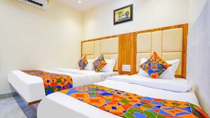 A hotel room with two beds, each with a colorful geometric-patterned bedspread. - Hotel Emirates Suite (Mumbai)