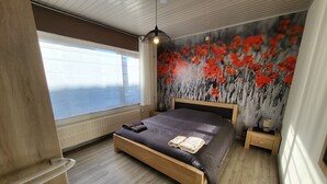 Un dormitorio moderno con una cama grande, cabecera de madera, una mesita de noche y un radiador.