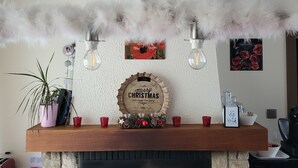 Una chimenea con un plato decorativo, una planta en maceta y una taza roja sobre la repisa.