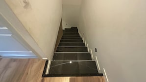 A staircase with black marble steps and wooden flooring.