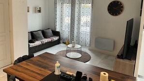 A modern living room with a sofa, a dining table, a small round table, and a TV.