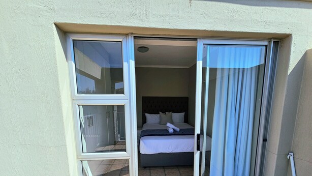 Une chambre d’hôtel avec un lit, une salle de bain avec douche et une porte-fenêtre coulissante donnant sur l’extérieur.