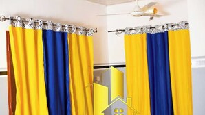 Een badkamer met gele en blauwe douchegordijnen, een plafondventilator en een handdoekhouder.