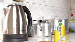 RVS keukenapparatuur, waaronder een waterkoker en pannen, op een betegeld aanrecht.