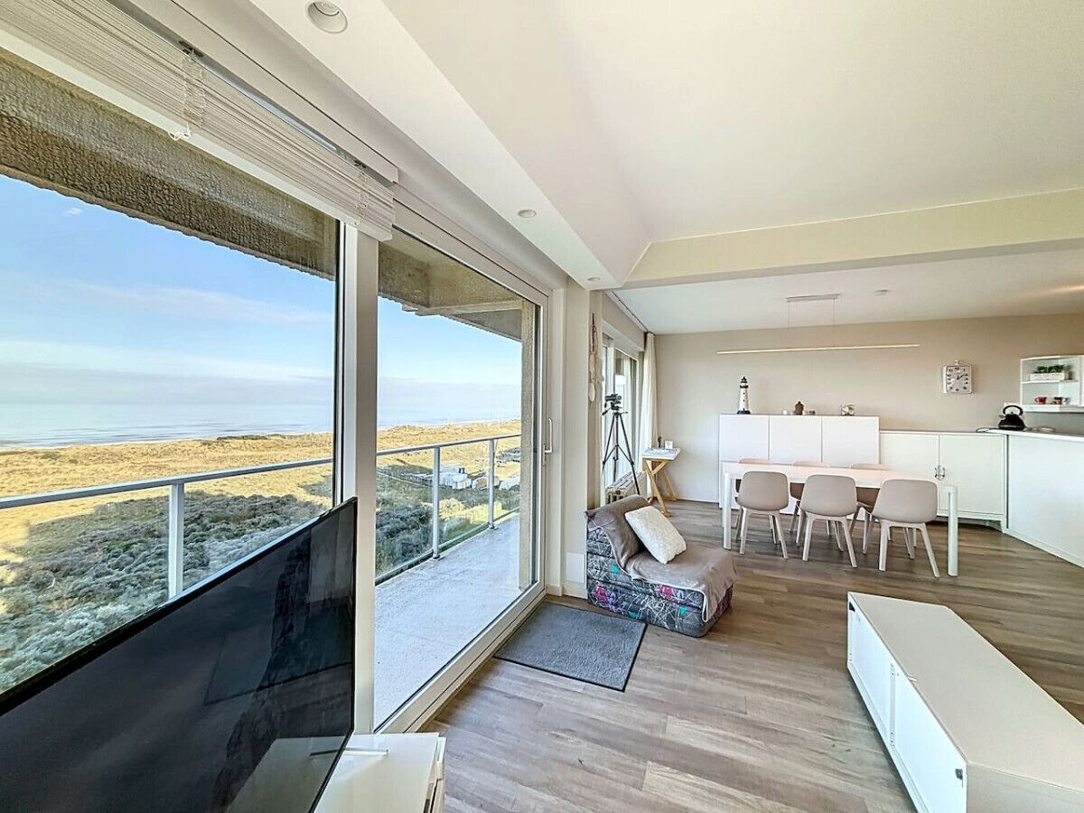 Una sala de estar moderna con un ventanal grande, una zona de estar acogedora y un comedor.