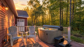 A wooden deck with two Adirondack chairs and a hot tub.
