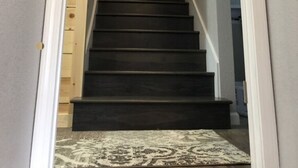 Una escalera con peldaños oscuros que conducen a un suelo de madera.