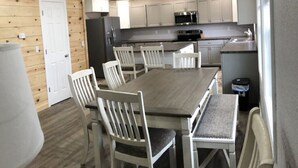 Una cocina compacta con armarios blancos, una isla central y una zona de comedor con mesa y sillas de madera.