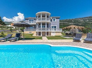 A two-story building with a pool, lounge chairs, and a dining area. - Exquisite Spacious Villa Bufaline with Pool and Gym - Eight Bedroom Villa with Pool and Gym (Kastel Novi)