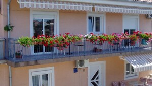 En tvåvåningsbyggnad med en balkong som är prydd med krukväxter och blommor.