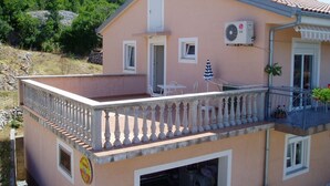 A two-story house with a balcony, a washing machine in the garage, and a mountain in the background.