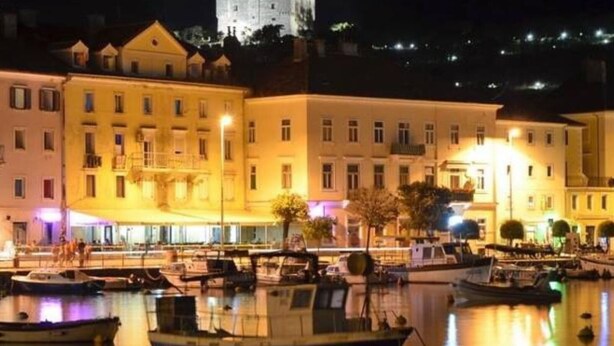 A waterfront area with buildings and a castle in the background.