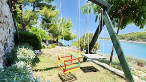Une balançoire installée dans un jardin, avec vue sur un lac et des arbres.