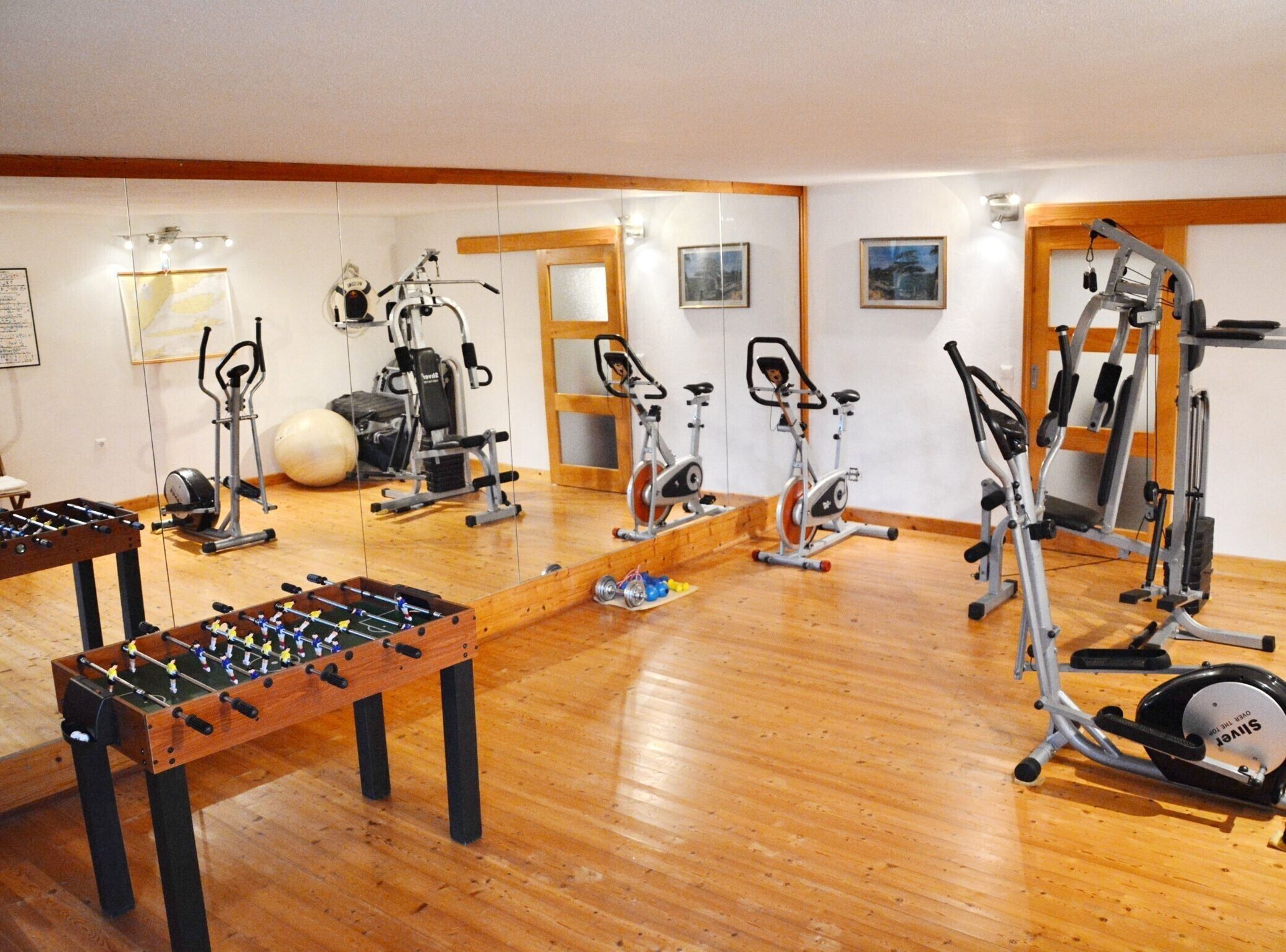 Una sala de gimnàstica amb equipament esportiu, una taula de futbolí i un sòl de fusta.