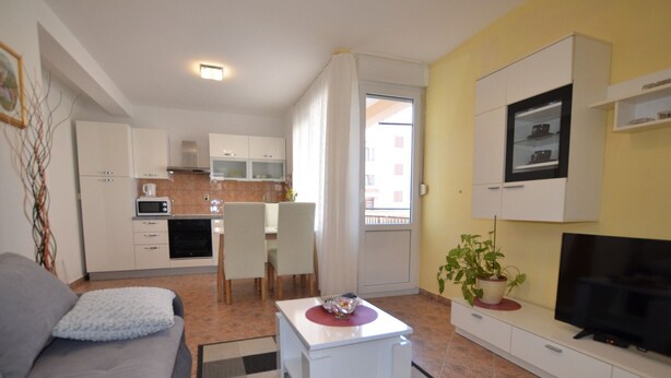 A compact living space with a sofa, a dining table, a TV, and a kitchen area. - Brigth and Breezy Rovinj Apartments - Standard One Bedroom Apartment (Rovinj)