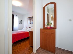 Ein Schlafzimmer mit einem hölzernen Schminktisch, einem Spiegel und einem Bett mit roter Bettdecke.