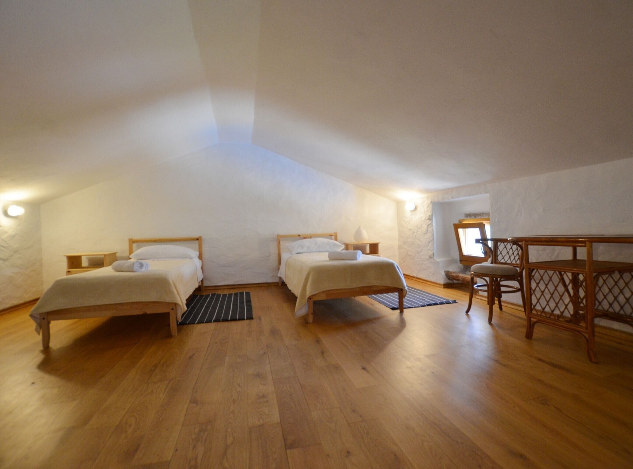 Ein Zimmer mit zwei Einzelbetten, einem Holztisch und einem Stuhl.