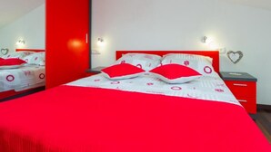 Une chambre décorée aux couleurs rouge et blanc, avec un lit, des tables de chevet et un miroir.