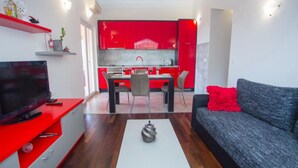 Un salon moderne avec un canapé gris, un mur d’accent rouge et un coin repas doté de meubles rouges.