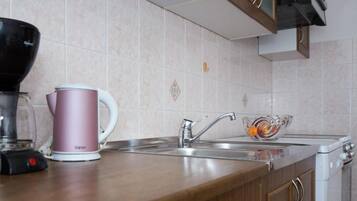 A kitchen with a coffee maker, a glass bowl, and a sink.