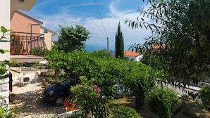 A residential area with a balcony, a car parked in the driveway, and lush greenery. - Apartments Marko - One Bedroom Apartment (Novi Vinodolski)