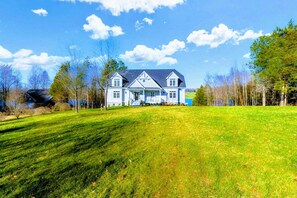A large, two-story house with a prominent front porch, surrounded by a well-maintained lawn and trees.
