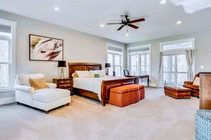 A bedroom with a bed, a chair, a desk, and a ceiling fan.