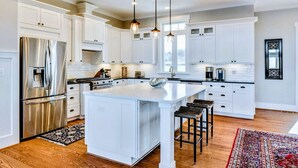 A modern kitchen with white cabinetry, stainless steel appliances, and pendant lighting.