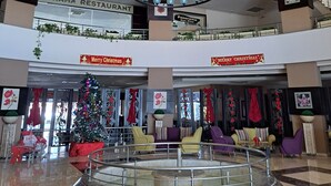 A spacious atrium with a central marble fountain, a Christmas tree, and seating areas.