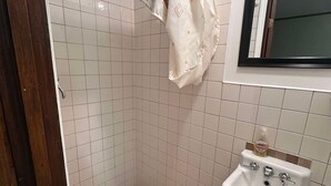 Un baño con ducha, lavamanos y ventana.
