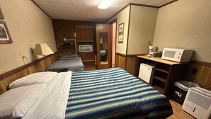 Habitación de hotel con dos camas, un escritorio con microondas, refrigerador y calentador.