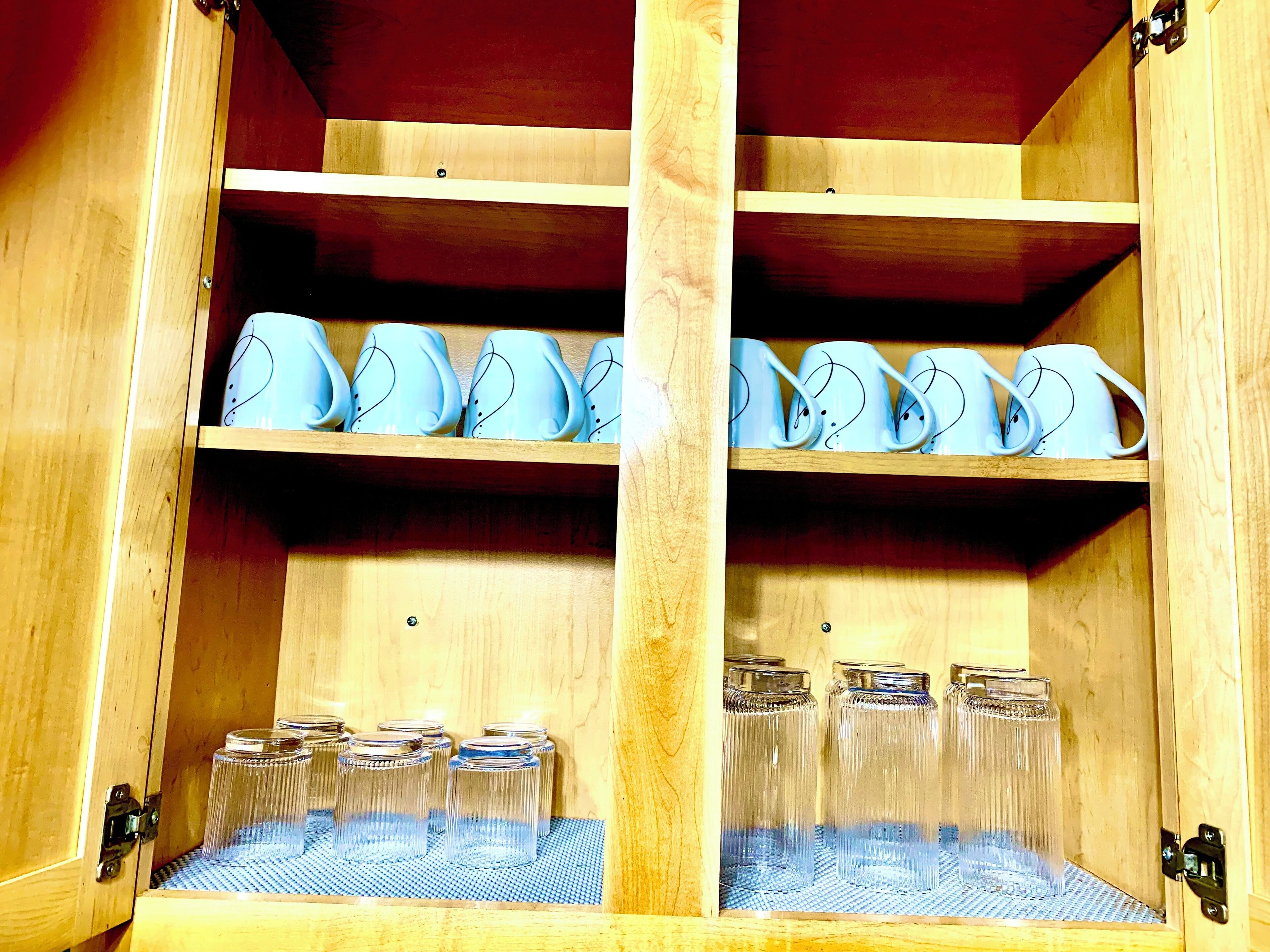 Un mueble de madera con estantes que contienen teteras de cerámica y frascos de vidrio.